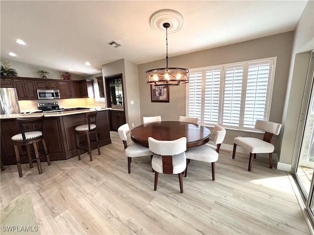 dining space featuring lofted ceiling, a notable chandelier, and light hardwood / wood-style flooring