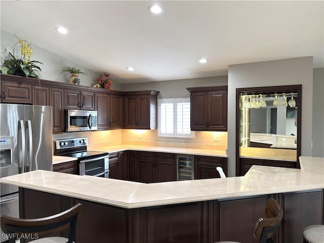 kitchen with stainless steel appliances, a kitchen bar, beverage cooler, and dark brown cabinetry