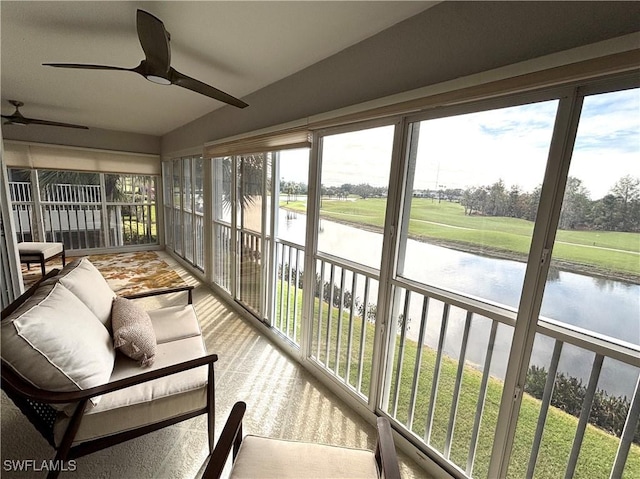 sunroom with ceiling fan and a water view