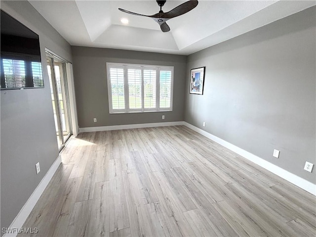 spare room featuring ceiling fan, baseboards, a raised ceiling, and wood finished floors