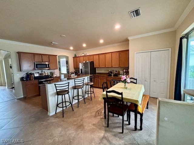 kitchen with a wealth of natural light, a kitchen island, a breakfast bar, and appliances with stainless steel finishes