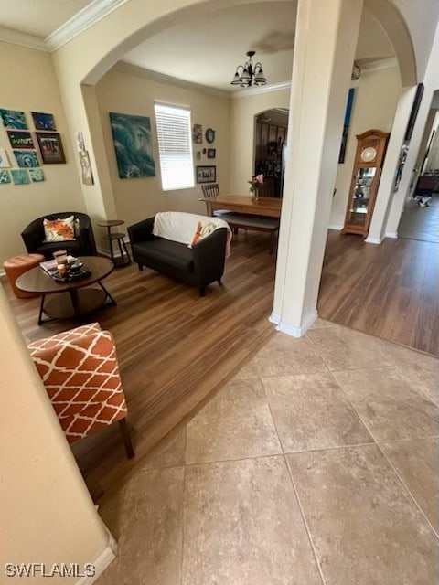 living room with crown molding, wood-type flooring, and a notable chandelier