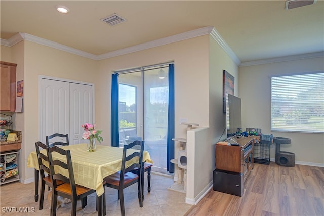 dining space with ornamental molding and light hardwood / wood-style flooring