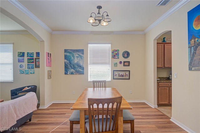 dining space with light hardwood / wood-style flooring, ornamental molding, and a chandelier