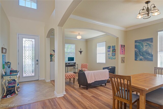 dining space with an inviting chandelier, crown molding, and light hardwood / wood-style floors