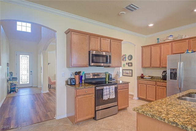 kitchen featuring ornamental molding, stainless steel appliances, dark stone counters, and light tile patterned floors