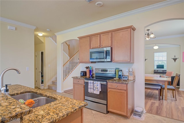 kitchen featuring light stone counters, sink, ornamental molding, and stainless steel appliances