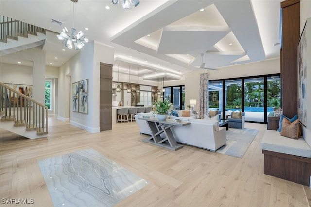 living room featuring plenty of natural light, a tray ceiling, and light wood-type flooring