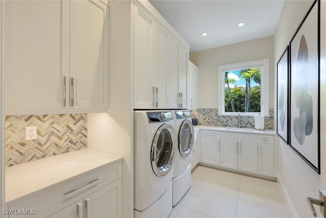 washroom with cabinets, washing machine and dryer, sink, and light tile patterned floors