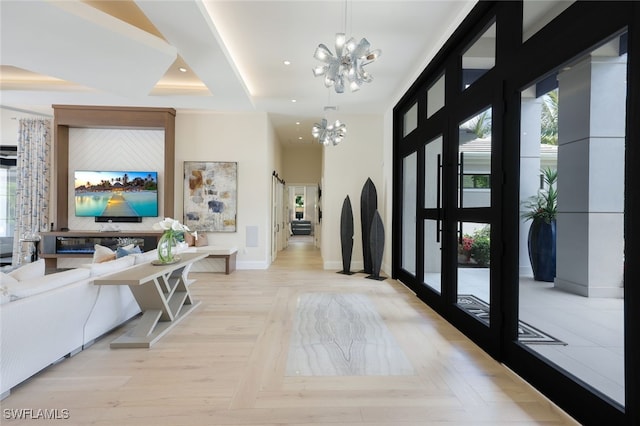 hall with a towering ceiling, light parquet flooring, and a chandelier