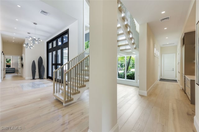 hallway with light hardwood / wood-style flooring and a notable chandelier