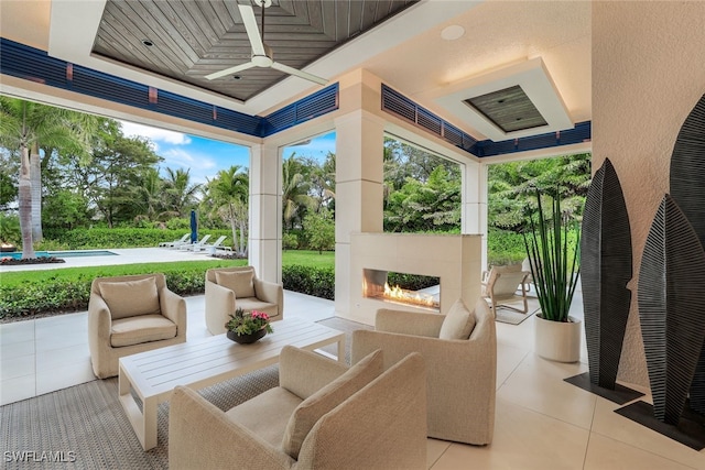 sunroom with ceiling fan and a multi sided fireplace