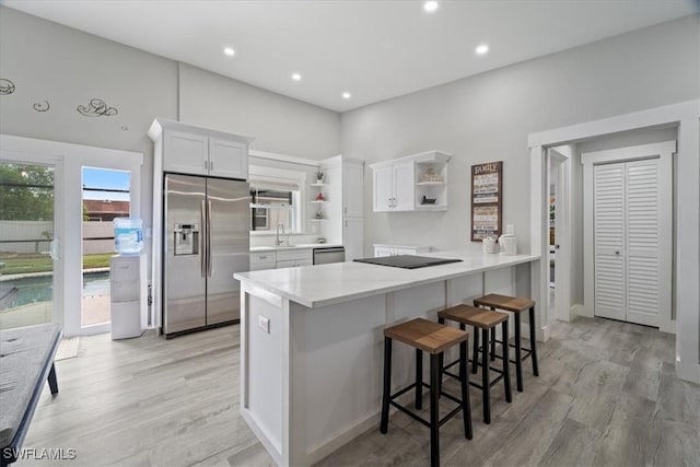 kitchen with stainless steel appliances, white cabinets, light wood-type flooring, and kitchen peninsula