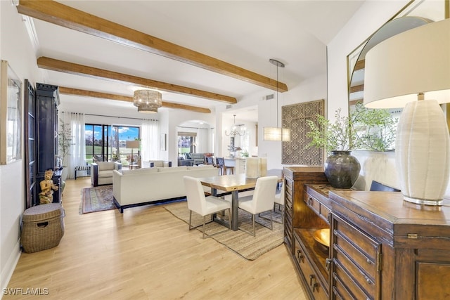 dining area featuring beam ceiling, a chandelier, and light wood-type flooring