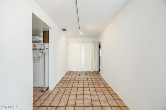 spare room featuring rail lighting and light tile patterned flooring