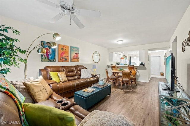 living area with ceiling fan, light wood finished floors, and baseboards