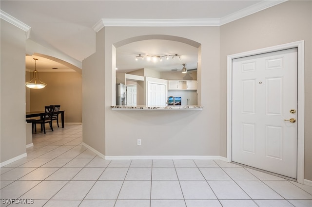 kitchen featuring pendant lighting, light tile patterned floors, stainless steel fridge, ornamental molding, and white cabinets