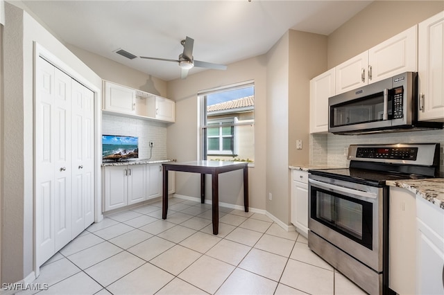 kitchen with backsplash, stainless steel appliances, light stone counters, white cabinets, and light tile patterned flooring