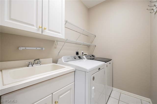 clothes washing area with cabinets, sink, washer and dryer, and light tile patterned floors