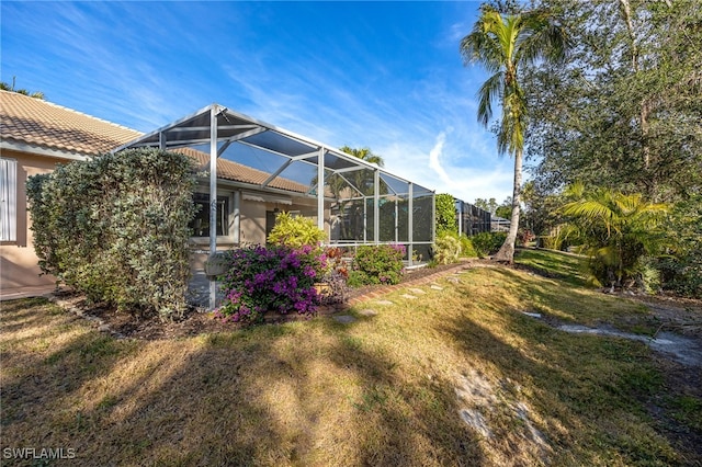 rear view of property with a lanai, a lawn, and a tiled roof