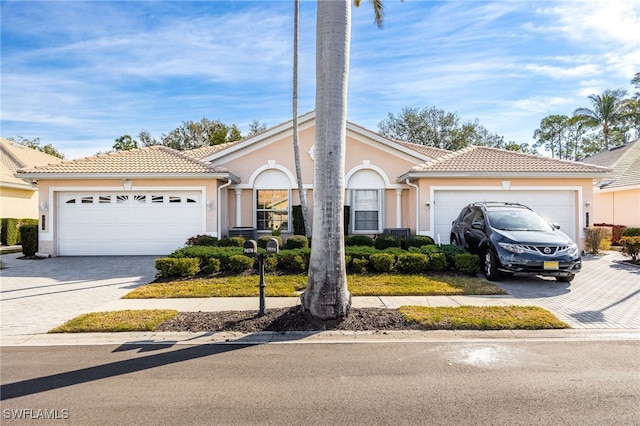 view of front of property with decorative driveway, an attached garage, and stucco siding