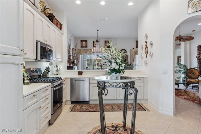 kitchen with light tile patterned flooring, white cabinetry, kitchen peninsula, pendant lighting, and stainless steel appliances