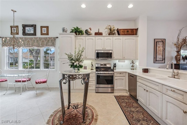 kitchen featuring appliances with stainless steel finishes, sink, a chandelier, hanging light fixtures, and light tile patterned floors