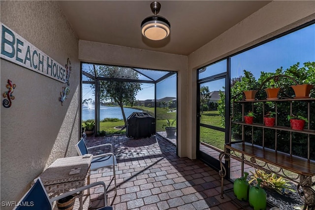 sunroom featuring a water view