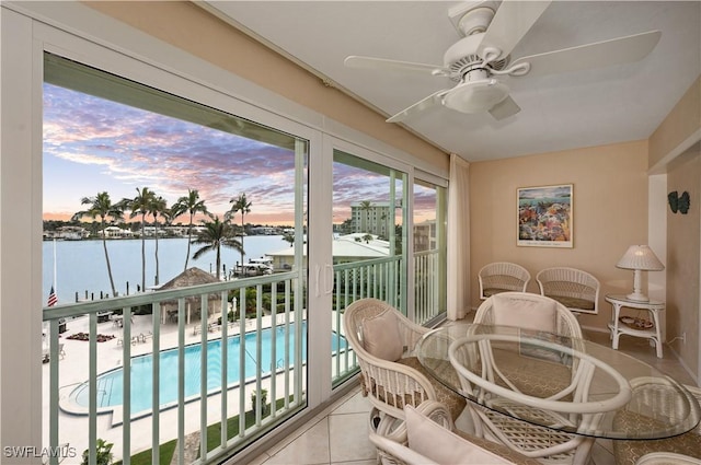 sunroom / solarium featuring a water view and ceiling fan