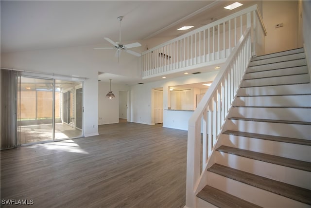 stairs with hardwood / wood-style floors, a towering ceiling, and ceiling fan