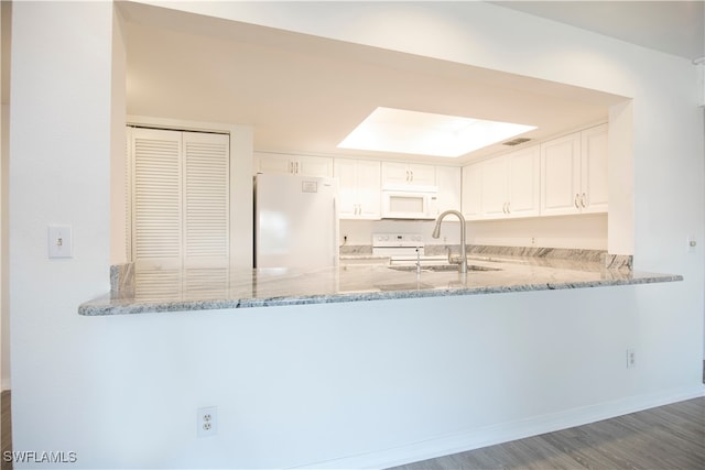 kitchen featuring white appliances, kitchen peninsula, sink, and white cabinets