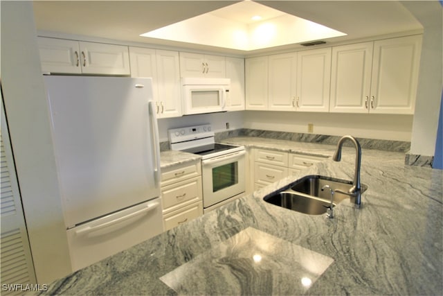 kitchen featuring sink, white appliances, a raised ceiling, and white cabinets