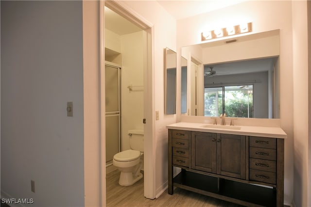 bathroom with a shower with door, ceiling fan, hardwood / wood-style floors, vanity, and toilet