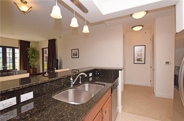 kitchen with dark stone countertops, sink, light carpet, and hanging light fixtures