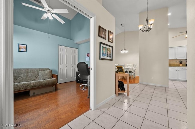 interior space with baseboards, high vaulted ceiling, light tile patterned flooring, and an inviting chandelier