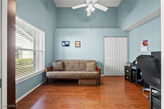 office space featuring a towering ceiling, baseboards, and wood finished floors