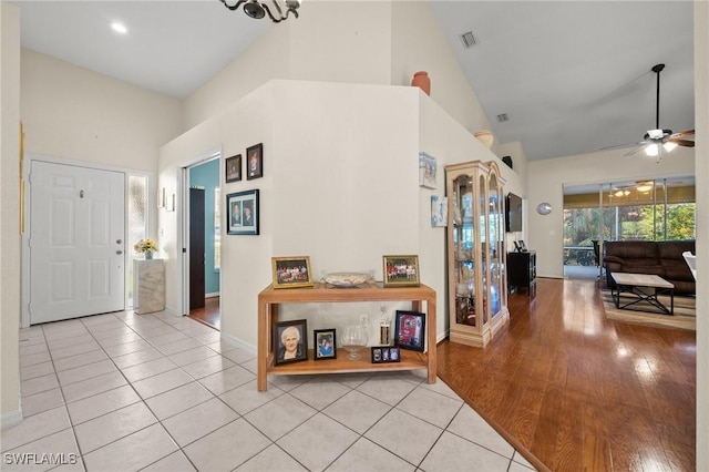 foyer with light tile patterned floors, high vaulted ceiling, and visible vents