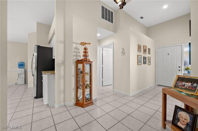 foyer entrance featuring a high ceiling, light tile patterned flooring, visible vents, and baseboards