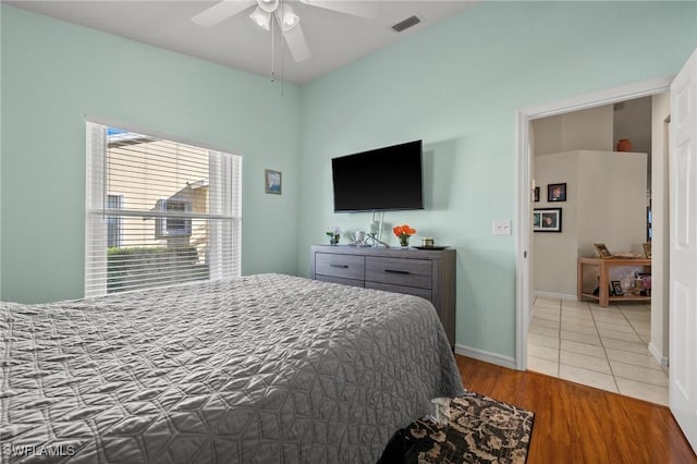 bedroom with ceiling fan, wood finished floors, visible vents, and baseboards