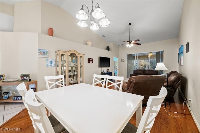 tiled dining room with vaulted ceiling, ceiling fan with notable chandelier, and visible vents