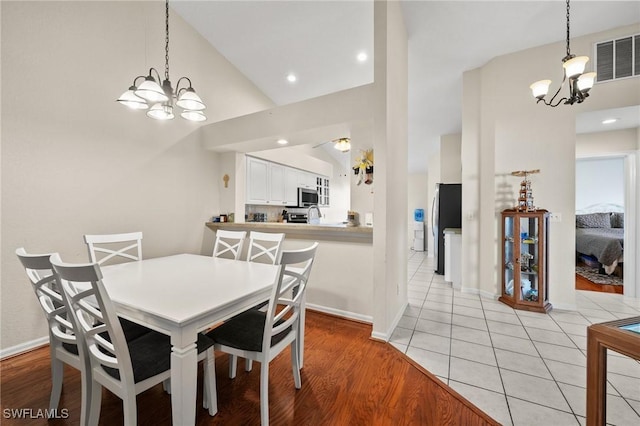 dining space featuring lofted ceiling, an inviting chandelier, light wood-style flooring, and visible vents