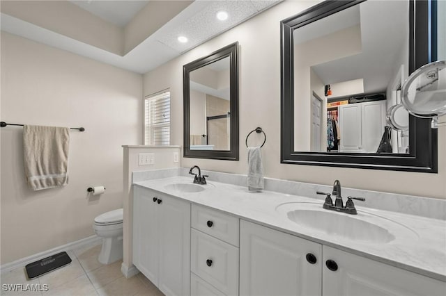 bathroom with double vanity, a sink, toilet, and tile patterned floors