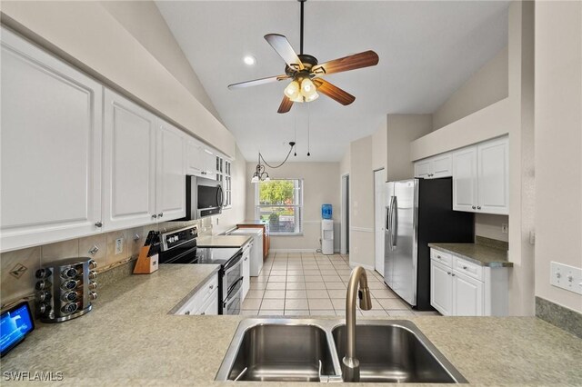 kitchen with lofted ceiling, white cabinetry, stainless steel appliances, and a sink