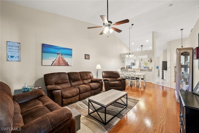 living area featuring wood-type flooring, high vaulted ceiling, and a ceiling fan