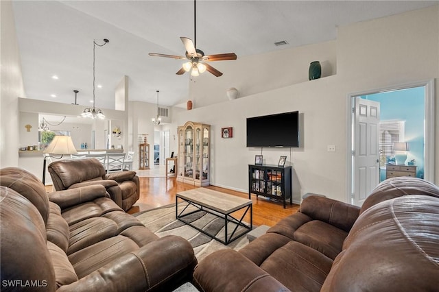 living room featuring high vaulted ceiling, visible vents, light wood-style flooring, and baseboards