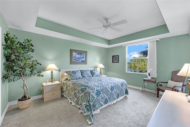 bedroom featuring ceiling fan, a tray ceiling, and carpet floors