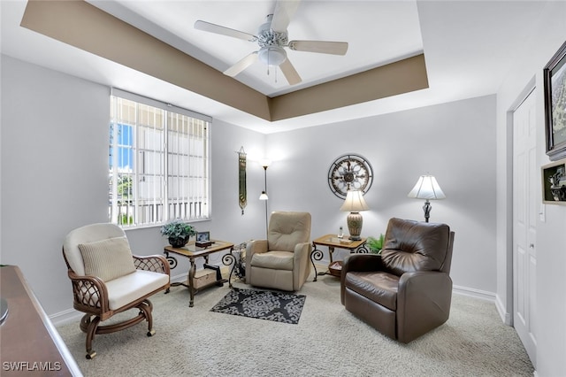 sitting room with a raised ceiling, ceiling fan, and carpet