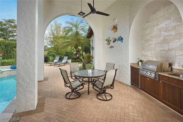 view of patio with sink, a fenced in pool, ceiling fan, a grill, and an outdoor kitchen