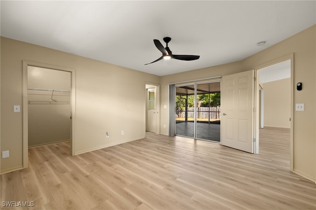 unfurnished bedroom featuring a walk in closet, light hardwood / wood-style flooring, access to outside, a closet, and ceiling fan