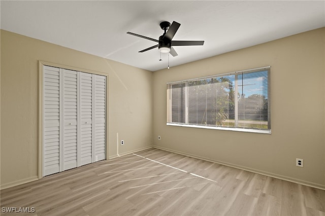 unfurnished bedroom featuring light hardwood / wood-style floors, ceiling fan, and a closet